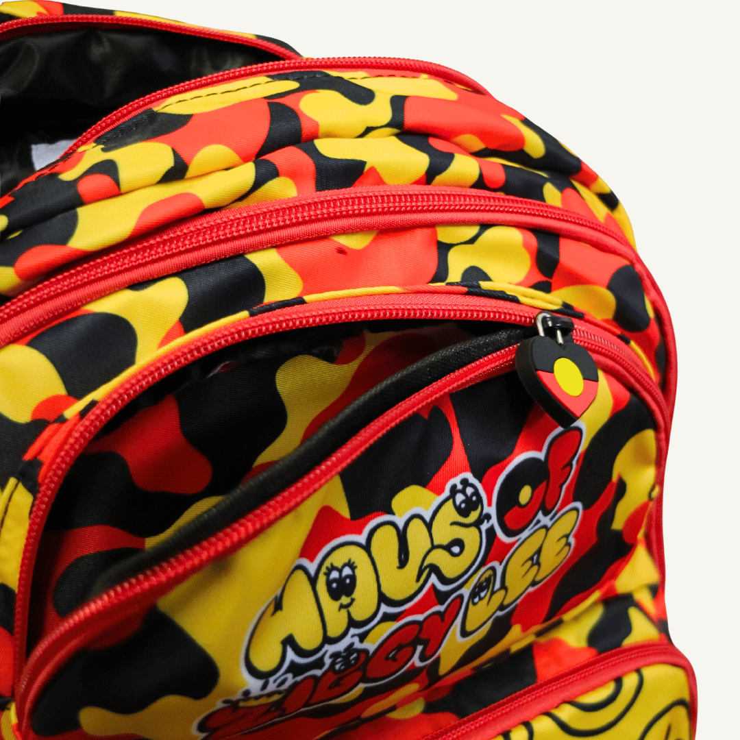 Close-up of haus of ziggy lee everyday deadly backpack with a bold red, yellow, and black camouflage pattern, featuring the 'Haus of Ziggy Lee' logo on the front pocket.